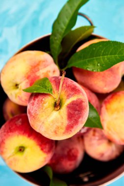 Olgun şeftali bir kapta, sepet mavi masada. Uzay kopyalayın. Düz yatıyordu. Üstten görünüm. 