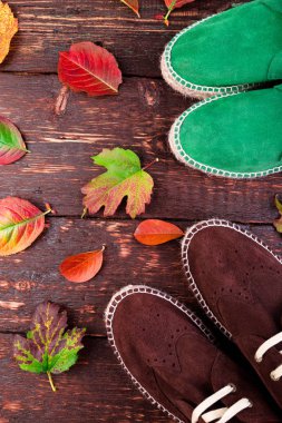 Kahverengi ve yeşil adam süet çizme ayakkabılarla, yaprakları ile ahşap arka plan üzerinde. Sonbahar ya da kış ayakkabı. iki çift. Düz yatıyordu. 