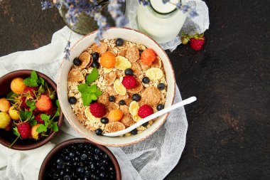 Sağlıklı vejetaryen kahvaltı. Yulaf ezmesi, granola ahududu ve yaban mersini kase üzerinde kahverengi zemin, buket lavanta ile. Üstten görünüm. Düz yatıyordu. 