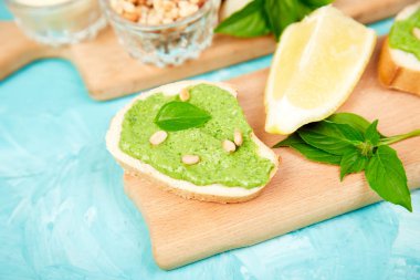 Bruschetta ekmek pesto sos, parmesan peyniri ve taze fesleğen ile mavi arka plan üzerinde bırakır. Abur cubur. Meze. Crostini. Italyan Mutfagi