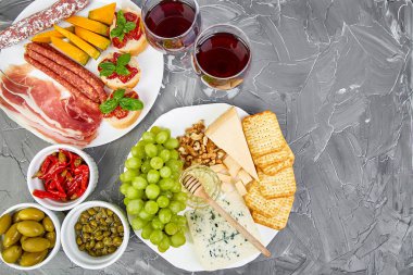 İtalyan antipasti aperatifler kümesi ve bardaklarda şarap şarap. Meze tabağı pastırma, salam, peynir, üzüm, zeytin, turşu ile catering, Prosciutto di Parma ile kavun, grunge gri arka plan üzerinde Brushettas. İtalyan gıda maddeleri. Mediterranean 