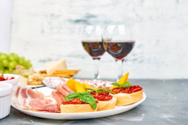 İtalyan antipasti aperatifler kümesi ve bardaklarda şarap şarap. Meze tabağı pastırma, salam, peynir, üzüm, zeytin, turşu ile catering, Prosciutto di Parma ile kavun, grunge gri arka plan üzerinde Brushettas. İtalyan gıda maddeleri. Mediterranean 