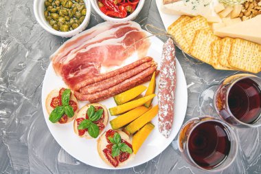 İtalyan antipasti şarap aperatifler küme. Meze tabağı pastırma, salam, peynir, üzüm, zeytin, turşu ile catering, Prosciutto di Parma ile kavun, grunge gri arka plan üzerinde Brushettas. İtalyan gıda maddeleri. Mediterranean 