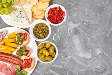 İtalyan antipasti şarap aperatifler küme. Meze tabağı pastırma, salam, peynir, üzüm, zeytin, turşu ile catering, Prosciutto di Parma ile kavun, grunge gri arka plan üzerinde Brushettas. İtalyan yemeği. Akdeniz. Teras yatıyordu. Kopya alanı.