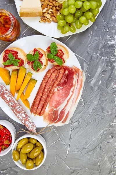 İtalyan antipasti şarap aperatifler küme. Meze tabağı pastırma, salam, peynir, üzüm, zeytin, turşu ile catering, Prosciutto di Parma ile kavun, grunge gri arka plan üzerinde Brushettas. İtalyan yemeği. Akdeniz. Teras yatıyordu. Kopya alanı. 
