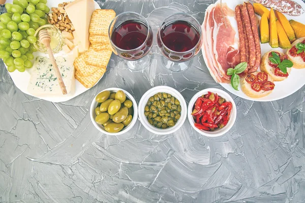 İtalyan antipasti şarap aperatifler küme. Meze tabağı pastırma, salam, peynir, üzüm, zeytin, turşu ile catering, Prosciutto di Parma ile kavun, grunge gri arka plan üzerinde Brushettas. İtalyan gıda maddeleri. Mediterranean 