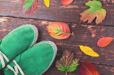 Yaprakları ile ahşap arka plan üzerinde ayakkabılarla yeşil adam süet çizmeler. Sonbahar ya da kış ayakkabı. Düz yatıyordu. 