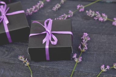 Mor Şerit ve buket çiçek lavanta siyah arka plan üzerine siyah hediye kutusu. Kutlama, Doğum günü. Dekorasyon mevcut. Düz yatıyordu. Kopya alanı.