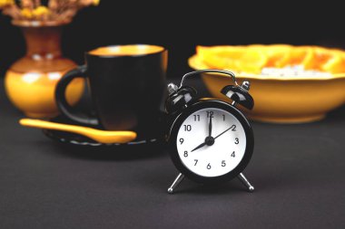 Sabah kahvesi, granola kahvaltı meyve çalar saat, sarı vazo çiçek siyah arka plan üzerine yakınındaki. 