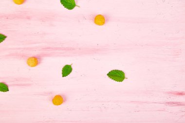 Düz yatıyordu desen sarı ahududu ve nane yaprakları üzerinde pembe bir arka plan ile. Sağlıklı diyet gıda kavramı. 