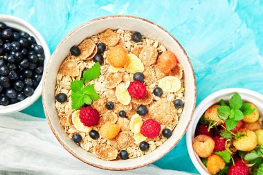 Sağlıklı vejetaryen kahvaltı. Yulaf ezmesi, granola ahududu ve yaban mersini kase üzerinde mavi arka plan, buket lavanta ile. Üstten görünüm. Düz yatıyordu. 