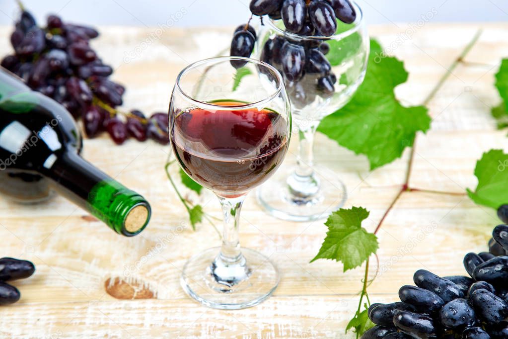 Red wine concept with bottle, glass and grapes on wooden background. Wine header image. Wineglasses