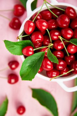 Pembe bir arka plan üzerinde beyaz kase kırmızı kiraz.