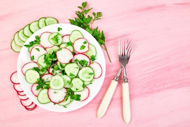 Taze salata salatalık ve turp pembe bir arka plan üzerinde. Düz yatıyordu. Üstten görünüm. Kopya alanı.