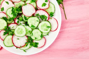 Taze salata salatalık ve turp pembe bir arka plan üzerinde. Düz yatıyordu. Üstten görünüm. Kopya alanı.
