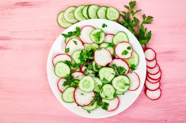 Taze salata salatalık ve turp pembe bir arka plan üzerinde. Düz yatıyordu. Üstten görünüm. Kopya alanı.
