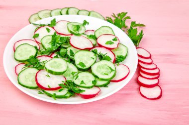 Taze salata salatalık ve turp pembe bir arka plan üzerinde.