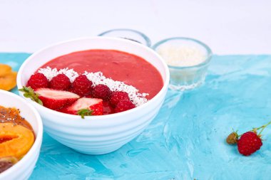 Güler yüzlü kase. Mavi arka plan üzerinde sağlıklı kahvaltı kase. Blackberry ve chia tohum ile kayısı güler yüzlü. Çilek ve Hindistan cevizi ile ahududu güler yüzlü. Vegan gıda