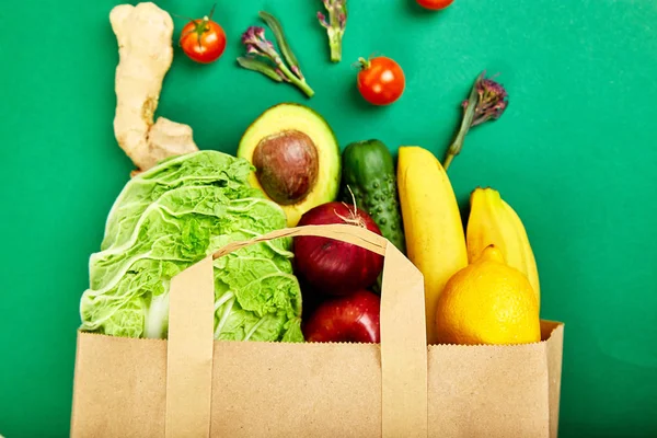 Grocering concept. Full paper bag of different fruits and vegetables,  ingredients for healthy cooking on a color background. healthy food.  Diet or vegan food, vegetarian. Top view. Flat lay.