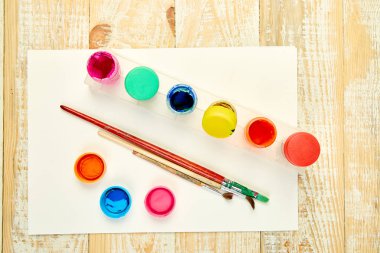 Suluboya paletleri ve boya fırçaları. Sanatçı ahşap arka plan üzerinde çalışma alanı. Çok az. Yaratıcı. Düz yatıyordu. Üstten görünüm. Kopya alanı. 