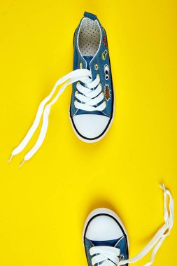 Mavi kadın ya da erkek spor ayakkabı sarı Kağıt arka plan üzerinde. Düz yatıyordu. Üstten görünüm. En az arka plan. Moda blog veya dergi kavramı. Uzay kopyalayın. Trendy 