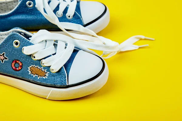 Blue female or male sneakers on yellow paper background. Flat lay. Top view. Minimal background. Fashion blog or magazine concept. Copy space. Trendy