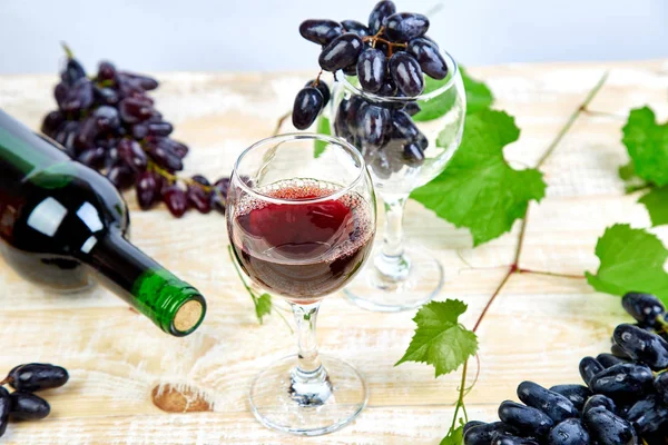 Red wine concept with bottle, glass and grapes on wooden background. Wine header image. Wineglasses