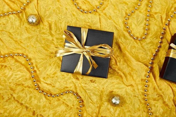 Luxury black gift boxes with gold ribbon on shine gold background. Christmas, birthday party. Flat lay. Copy space. Top view.
