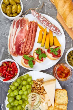 İtalyan antipasti şarap aperatifler küme. Meze tabağı pastırma, salam, peynir, üzüm, zeytin, turşu ile catering, Prosciutto di Parma ile kavun, grunge gri arka plan üzerinde Brushettas. İtalyan yemeği. Akdeniz. Teras yatıyordu. Kopya alanı. 