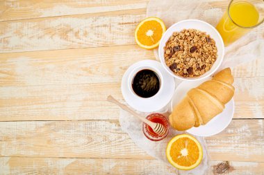 Günaydın. Continental kahvaltı Ristiç ahşap arka plan üzerinde. Bir fincan kahve, portakal suyu, kruvasan, granola müsli yukarıdan ahşap tepsi. Üstten görünüm. Düz yatıyordu. Uzay kopyalayın. Düzen