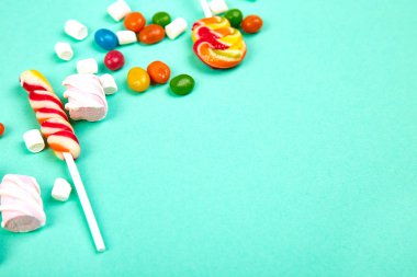 Pastel turkuaz arka plan üzerinde renkli şekerler. Düz yatıyordu, en iyi görünüm. Lolipop ve hatmi Kağıt adam üzerinde