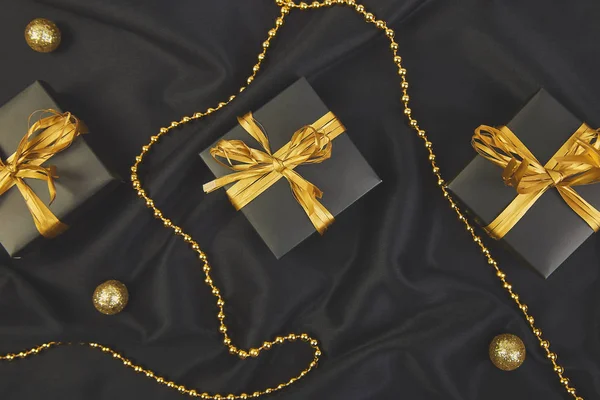 Luxury black gift boxes with gold ribbon on shine background. Christmas, birthday party presents. Flat lay. Copy space. Top view.