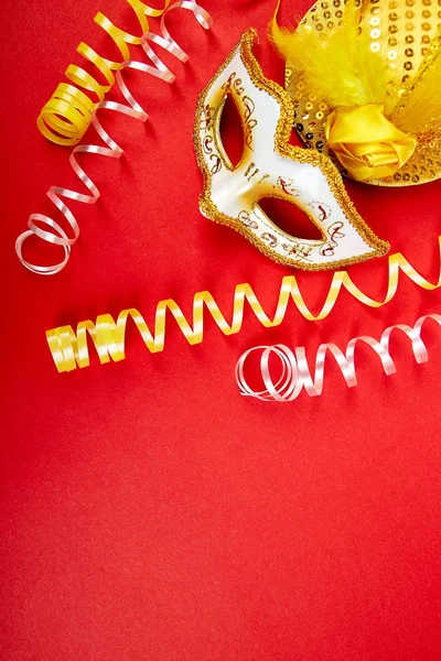 Kırmızı zemin üzerine sarı ve beyaz karnaval maskesi. Üstten görünüm maskeli balo arka plan görüntüsü. Düz yatıyordu. Mardi Gras kutlamaları kavramı. Kopya alanı.