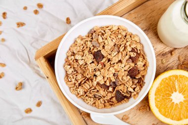 Günaydın. Beyaz çarşaf üzerinde Odaya Servis Kahvaltı. Müsli veya granola, süt, portakal yukarıdan ahşap tepsi. Üstten görünüm. Düz yatıyordu. Uzay kopyalayın. Otel odasında sabah erken.