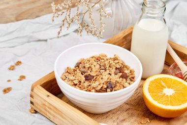 Günaydın. Beyaz çarşaf üzerinde Odaya Servis Kahvaltı. Müsli veya granola, süt, portakal yukarıdan ahşap tepsi. Üstten görünüm. Düz yatıyordu. Uzay kopyalayın. Otel odasında sabah erken.