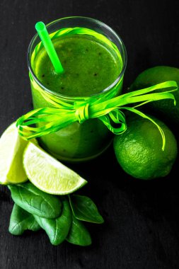 Ispanak ve kireç yüzlü. Siyah masada malzemelerle karışık yeşil smoothie. Sağlıklı, vegan, diyet. Detoks