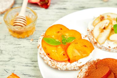 Pirinç gevrek ekmek tropikal meyve - nar, mandalina, Trabzon hurması, apple ile sağlıklı snack. Beyaz bir arka plan kolay kahvaltı yakın çekim. Yaz vegan, beslenme, organik doğal gıda. Kopya alanı.