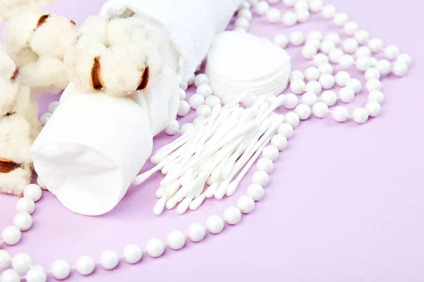 stock image Branch of cotton plant, eared sticks, cotton pads, towel, cosmetic makeup removers tampons, hygienic sanitary swabs  on purple background Top view. Spa concept. Flat lay. Copy space.