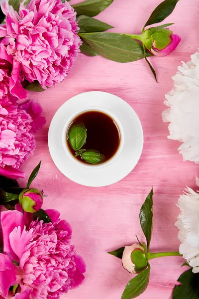 Bouquet Peony flowers on pink backgroun and  cup of coffee. flat lay. Good morning.