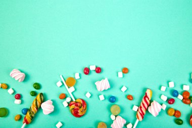 Pastel turkuaz arka plan üzerinde renkli şekerler. Düz yatıyordu, en iyi görünüm. Lolipop ve hatmi Kağıt adam üzerinde
