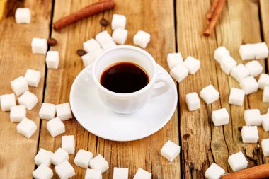 Bir fincan kahve espresso yakınındaki rustik ahşap masa üzerinde küp şeker. 