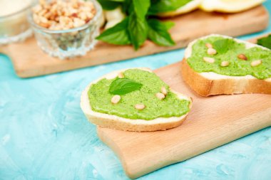 Bruschetta ekmek pesto sos, parmesan peyniri ve taze fesleğen ile mavi arka plan üzerinde bırakır. Abur cubur. Meze. Crostini. Italyan Mutfagi