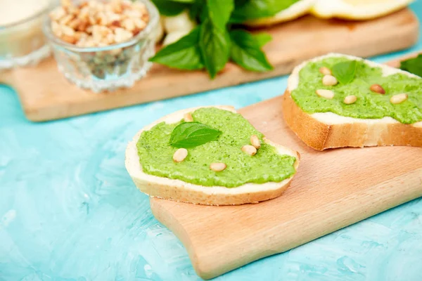 Bruschetta ekmek pesto sos, parmesan peyniri ve taze fesleğen ile mavi arka plan üzerinde bırakır. Abur cubur. Meze. Crostini. Italyan Mutfagi