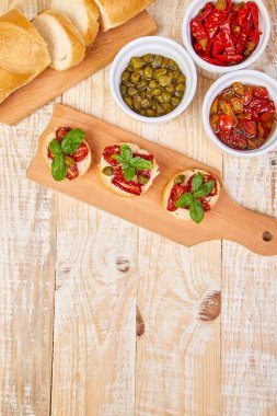 Bruschetta veya crostini ile güneş domates ve kapari ahşap mutfak tahtası ahşap arka plan ile kurutulmuş. Taze İtalyan sandviç. Lezzetli aperatif ve meze. Meze. Teras yatıyordu. Uzay kopyalayın. üstten görünüm. 