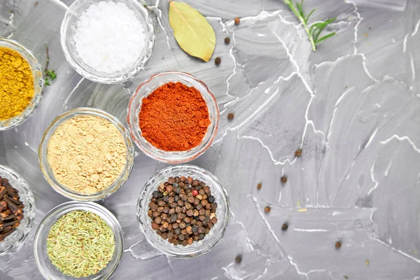 Seasoning background. Spice and herb seasoning with fresh and dried herbs and spices in bowls. Colourful various herbs and spices for cooking on grey background. Top view. Copy space
