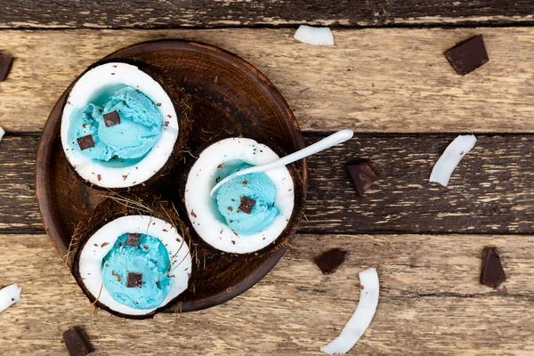 青い木製の背景にココナッツ ボウルにチョコレートとアイスクリーム 夏の食べ物 平面図です コピー スペース — ストック写真