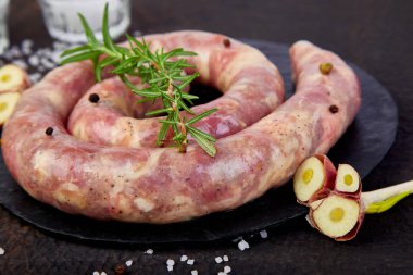 Biberiye, tuz ve siyah arduvaz plaka üzerinde peper ham sarmal domuz sosisi