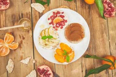 Pirinç gevrek ekmek tropikal meyve - nar, mandalina, Trabzon hurması, apple ile sağlıklı snack. Rustik bir arka plan üzerinde kolay kahvaltı. Yaz vegan, beslenme, organik doğal gıda
