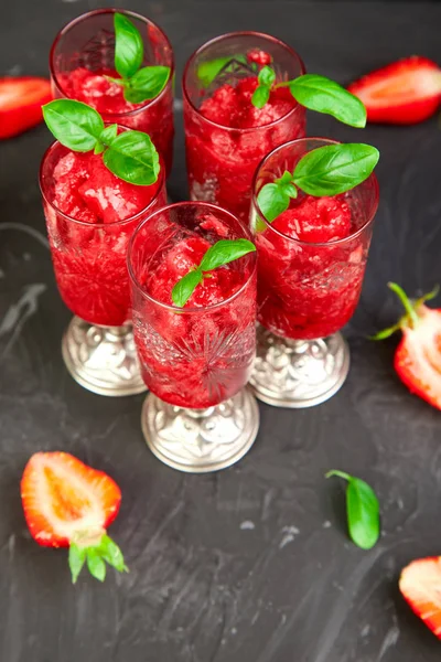 Summer refreshing strawberry sorbet, slush granita drink in serving glasses. Healthy low calorie summer treat, dessert. Iced Cocktail on black background.