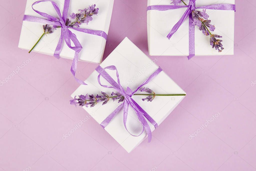 White Gift box with violet ribbon and bouquet of flower lavender on pink background. Celebration, birthday. Decoration present. Flat lay. Copy space.